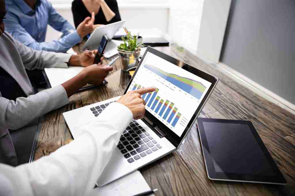 Side View Of Businesspeople Examining Graph On Computer At Workplace