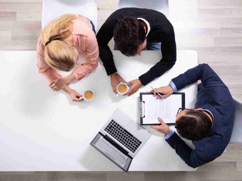 Happy,Young,Couple,Consulting,Male,Friendly,Financial,Advisor,With,Coffee